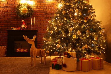 Photo of Beautiful tree with festive lights, wooden deer and Christmas gifts in living room. Interior design