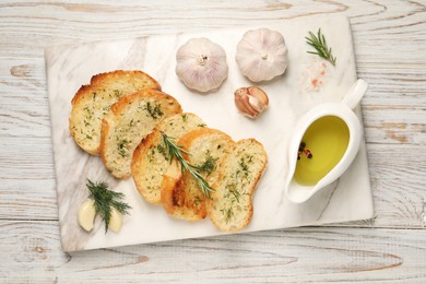 Photo of Tasty baguette with garlic, dill, rosemary and oil on white wooden table, top view