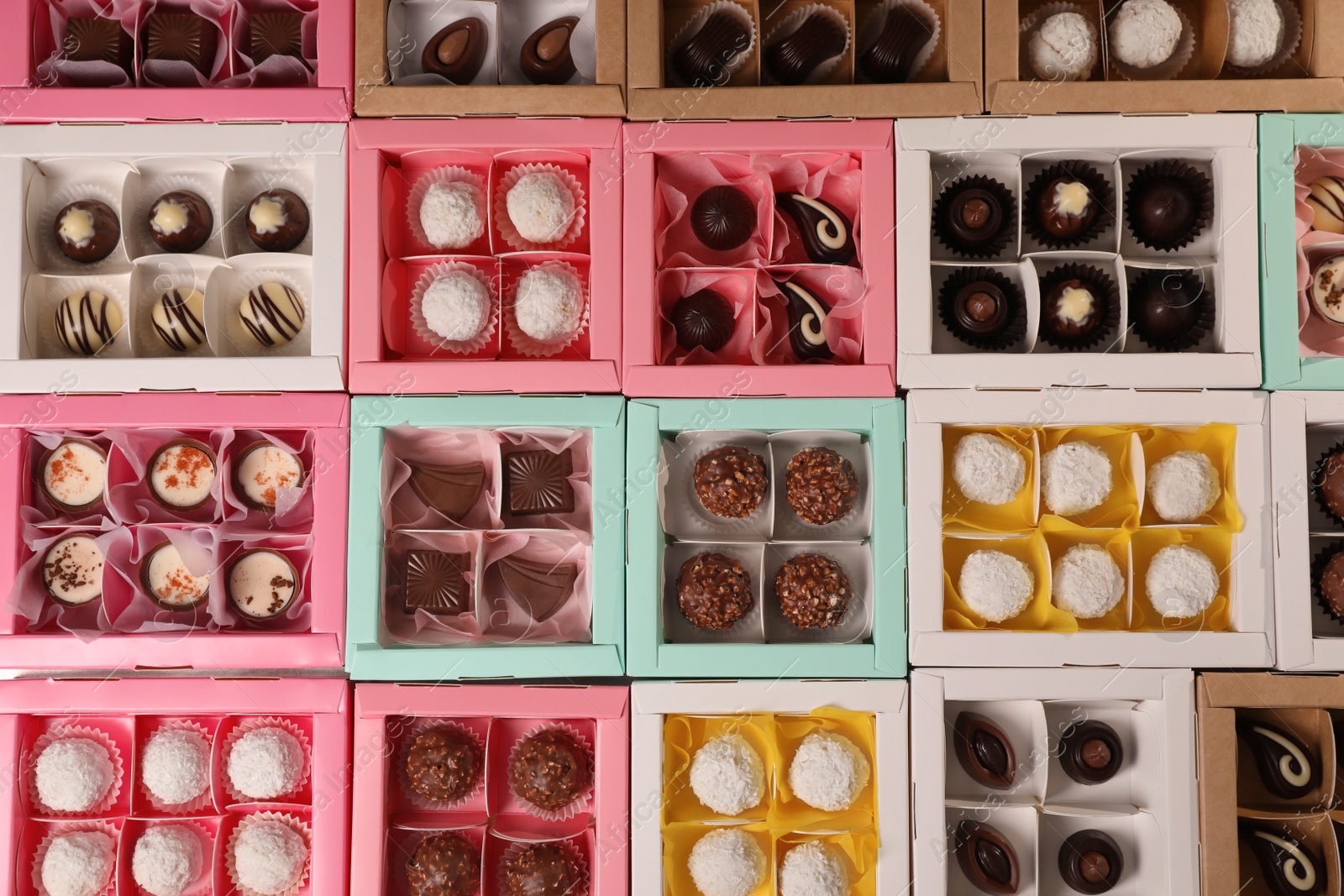 Photo of Many delicious candies in boxes, top view. Production line