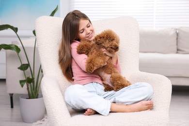 Photo of Little child with cute puppy in armchair at home. Lovely pet