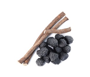 Photo of Many tasty candies and dried sticks of liquorice root isolated on white, top view