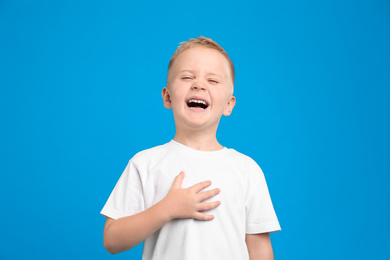 Photo of Portrait of cute little boy on light blue background