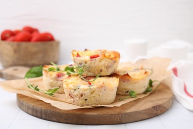 Photo of Delicious egg muffins with cheese on white tiled table, closeup