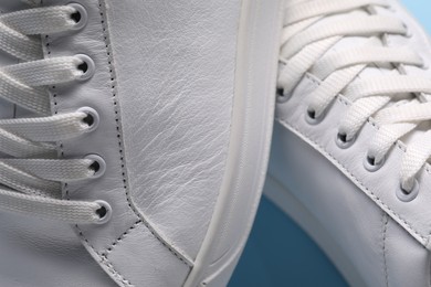 Photo of Pair of stylish white sneakers on light blue background, closeup