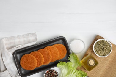 Photo of Uncooked breaded cutlets on white wooden table, flat lay. Freshly frozen semi-finished product