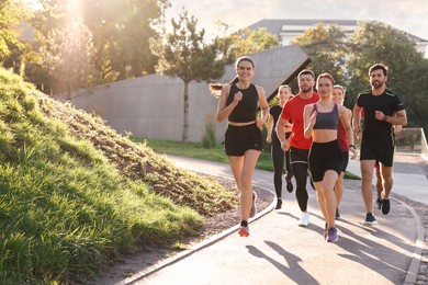 Photo of Group of people running outdoors on sunny day. Space for text