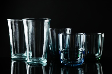 Photo of Set of different colorful empty glasses on black background