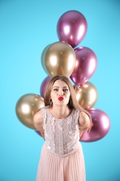 Photo of Young woman with air balloons on color background