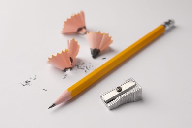 Photo of Graphite pencil, shavings and sharpener on white background, closeup