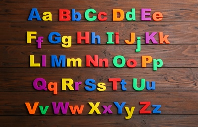 Photo of Colorful magnetic letters on wooden background, flat lay. Alphabetical order