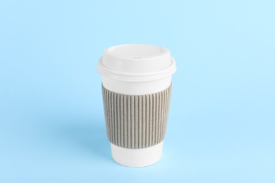 Paper cup with plastic lid on light blue background. Coffee to go