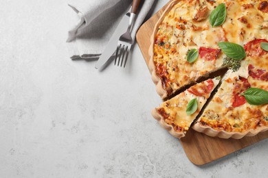 Photo of Tasty quiche with tomatoes, basil and cheese served on light textured table, flat lay. Space for text
