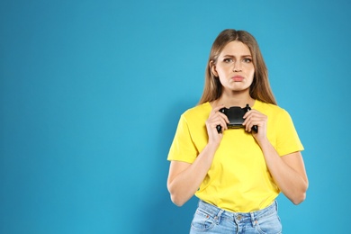 Photo of Emotional young woman playing video games with controller on color background. Space for text