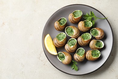 Photo of Delicious cooked snails with parsley and lemon on light table, top view. Space for text