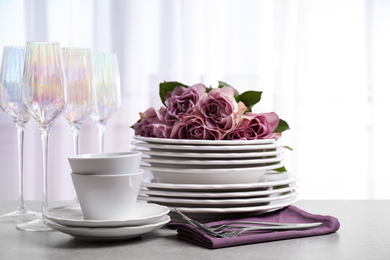 Photo of Set of glasses and dishes with flowers on light grey table