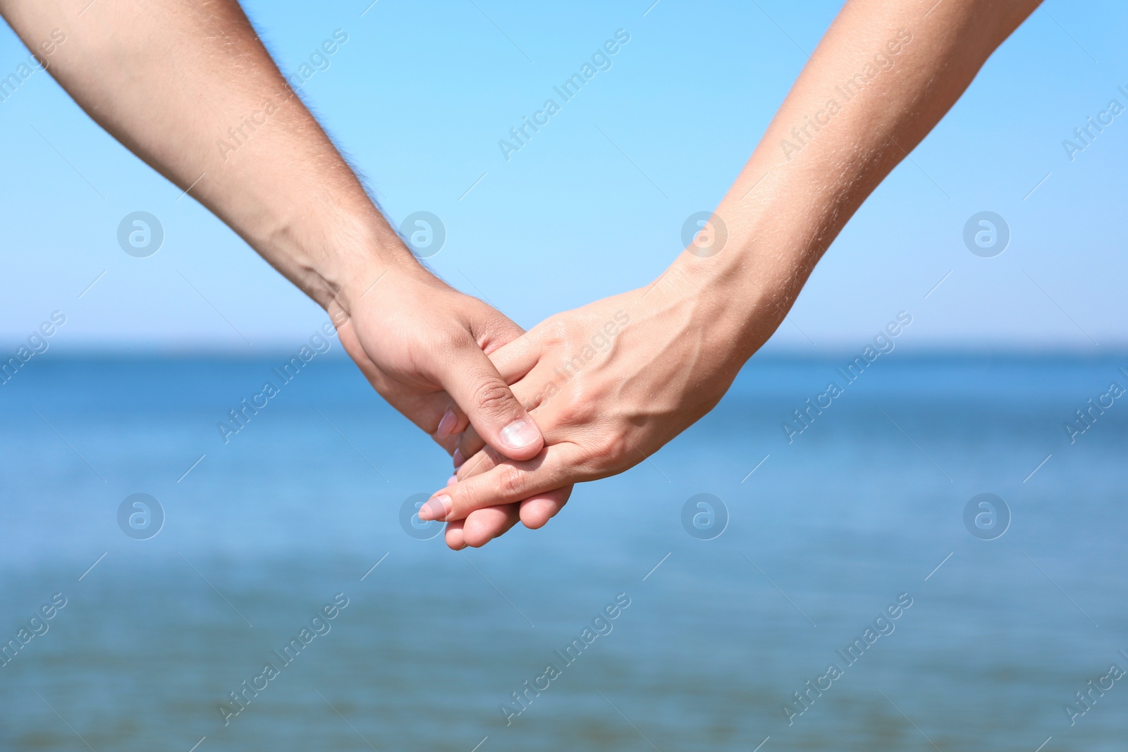 Photo of Happy couple holding hands at beach on sunny day, closeup