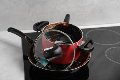 Photo of Stack of dirty kitchenware on cooktop in kitchen