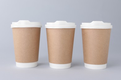 Photo of Paper cups with white lids on light grey background. Coffee to go