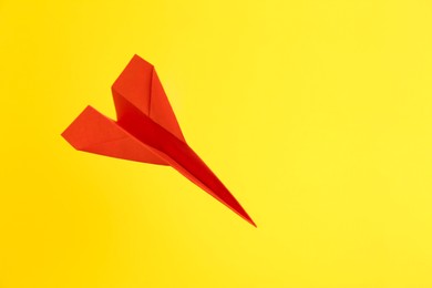 Photo of Handmade red paper plane on yellow background. Space for text