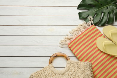 Photo of Beach bag, towel and flip flops on white wooden background, flat lay. Space for text