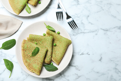 Photo of Tasty spinach crepes served on white marble table, flat lay. Space for text