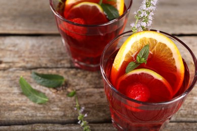Photo of Glasses of delicious refreshing sangria on old wooden table, closeup. Space for text