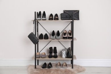 Photo of Shelving unit with stylish shoes and purses near white wall. Element of dressing room interior