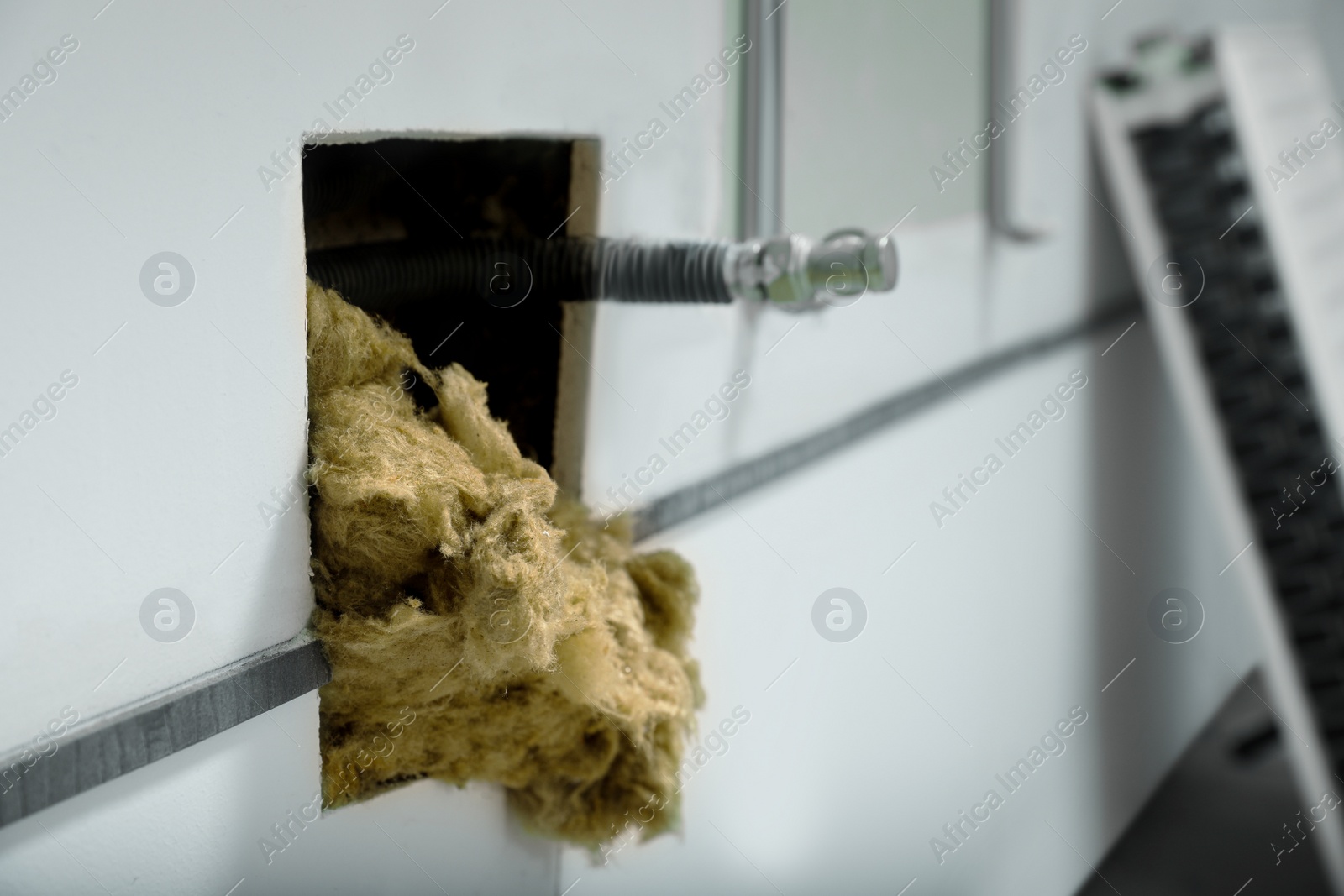 Photo of Hole in wall with metal pipe and thermal insulation material, closeup. Space for text