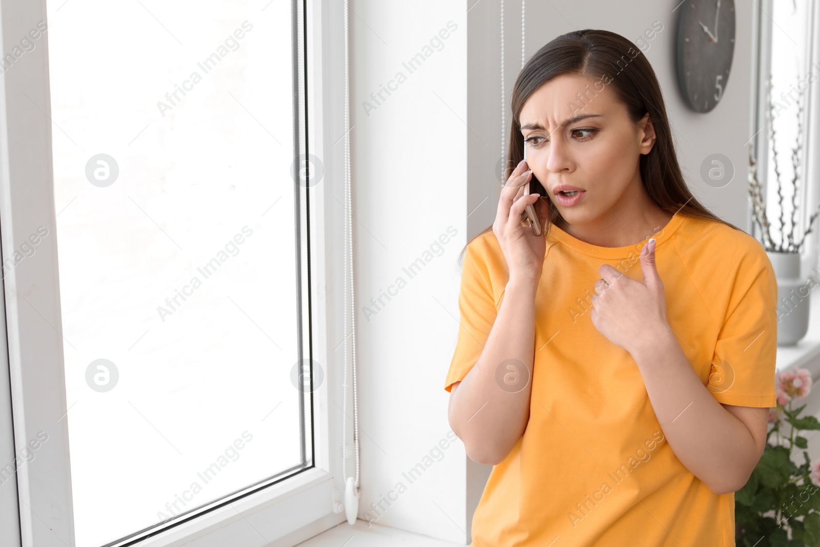 Photo of Woman arguing on mobile phone near window at home