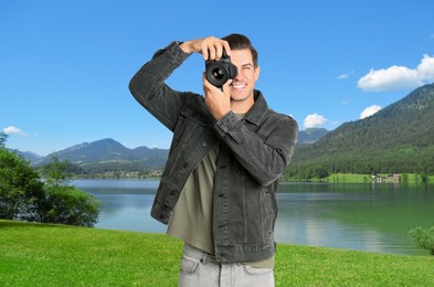 Photographer holding professional camera and beautiful landscape with mountains and river on background