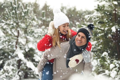 Beautiful happy couple in snowy forest on winter day