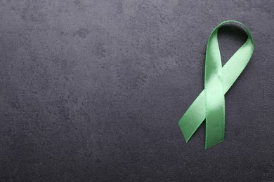 World Mental Health Day. Green ribbon on black background, top view with space for text