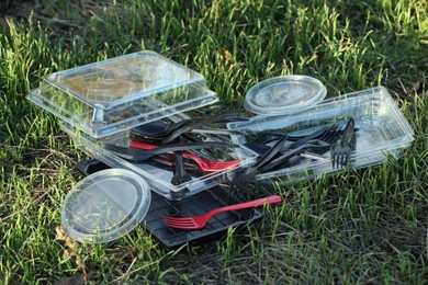 Photo of Used plastic tableware on grass outdoors. Environmental pollution concept