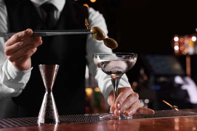 Photo of Bartender preparing fresh Martini cocktail at bar counter, closeup