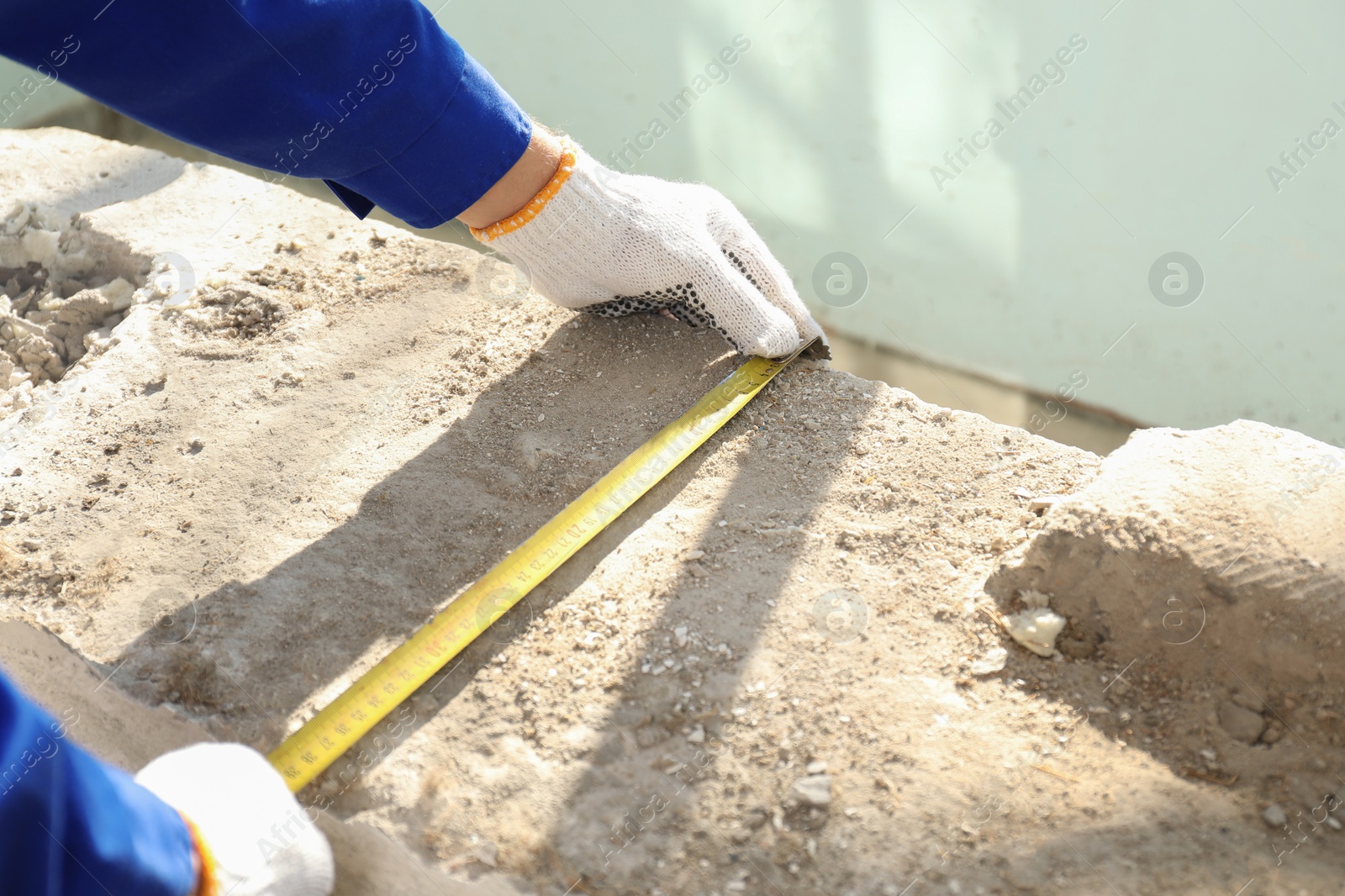 Photo of Worker taking measurement for window installation indoors, closeup