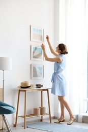 Photo of Female interior designer decorating white wall with pictures indoors