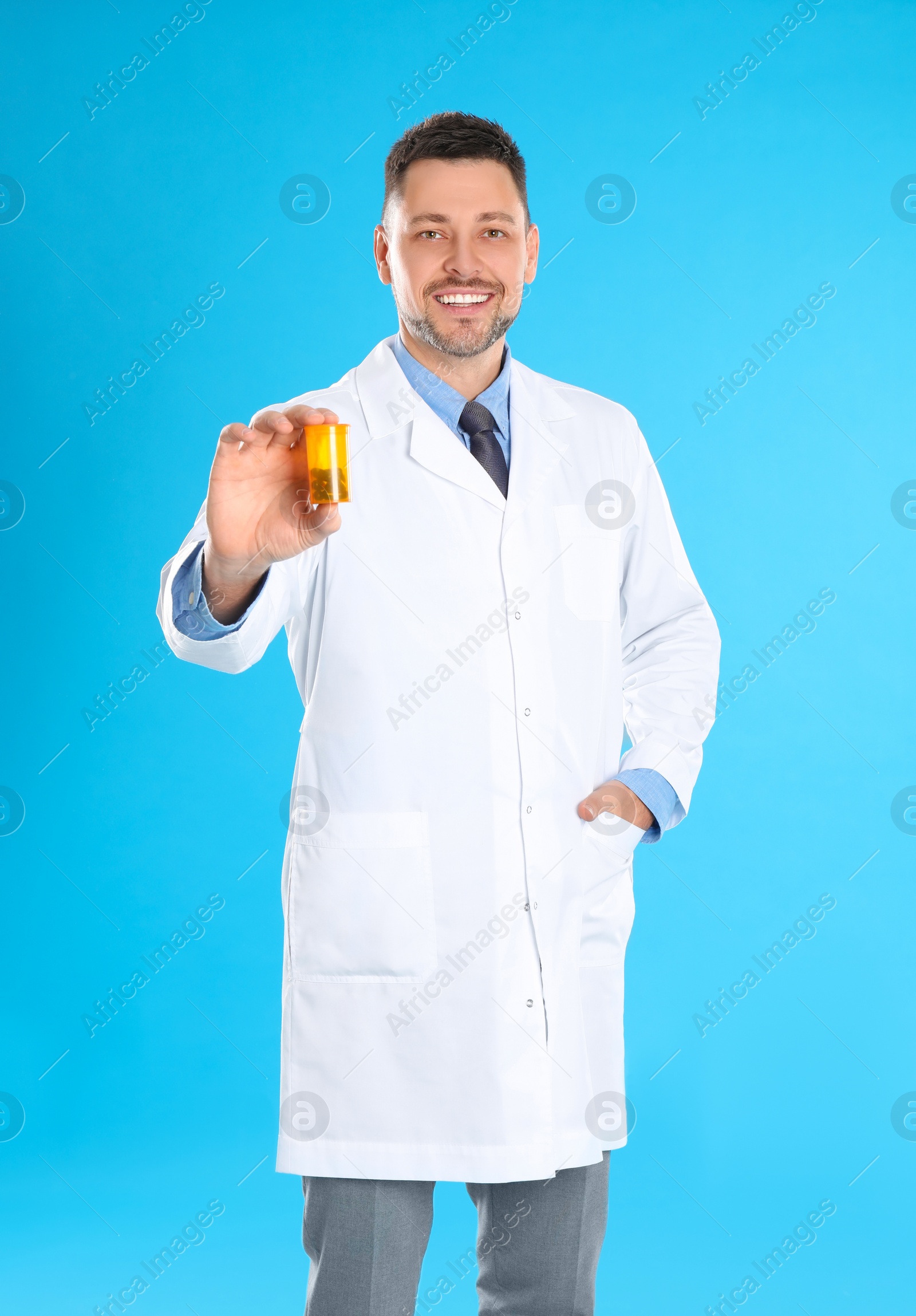 Photo of Professional pharmacist with pills on light blue background