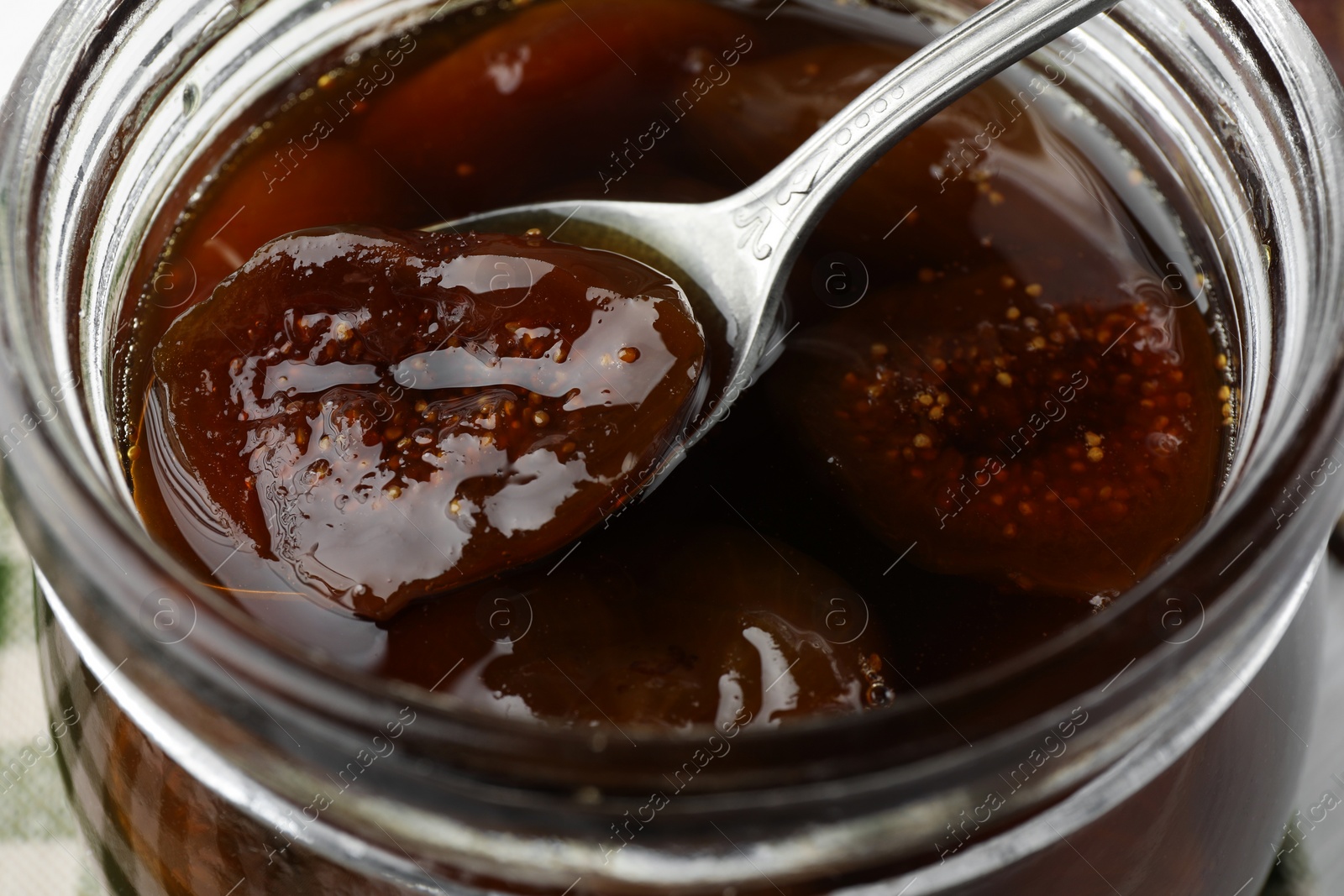 Photo of Jar of tasty sweet fig jam on table, closeup