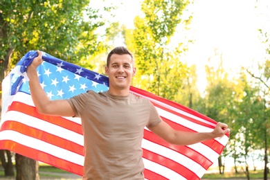 Photo of Man with American flag in park on sunny day