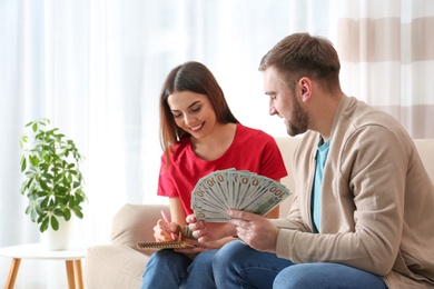 Beautiful young couple with money at home