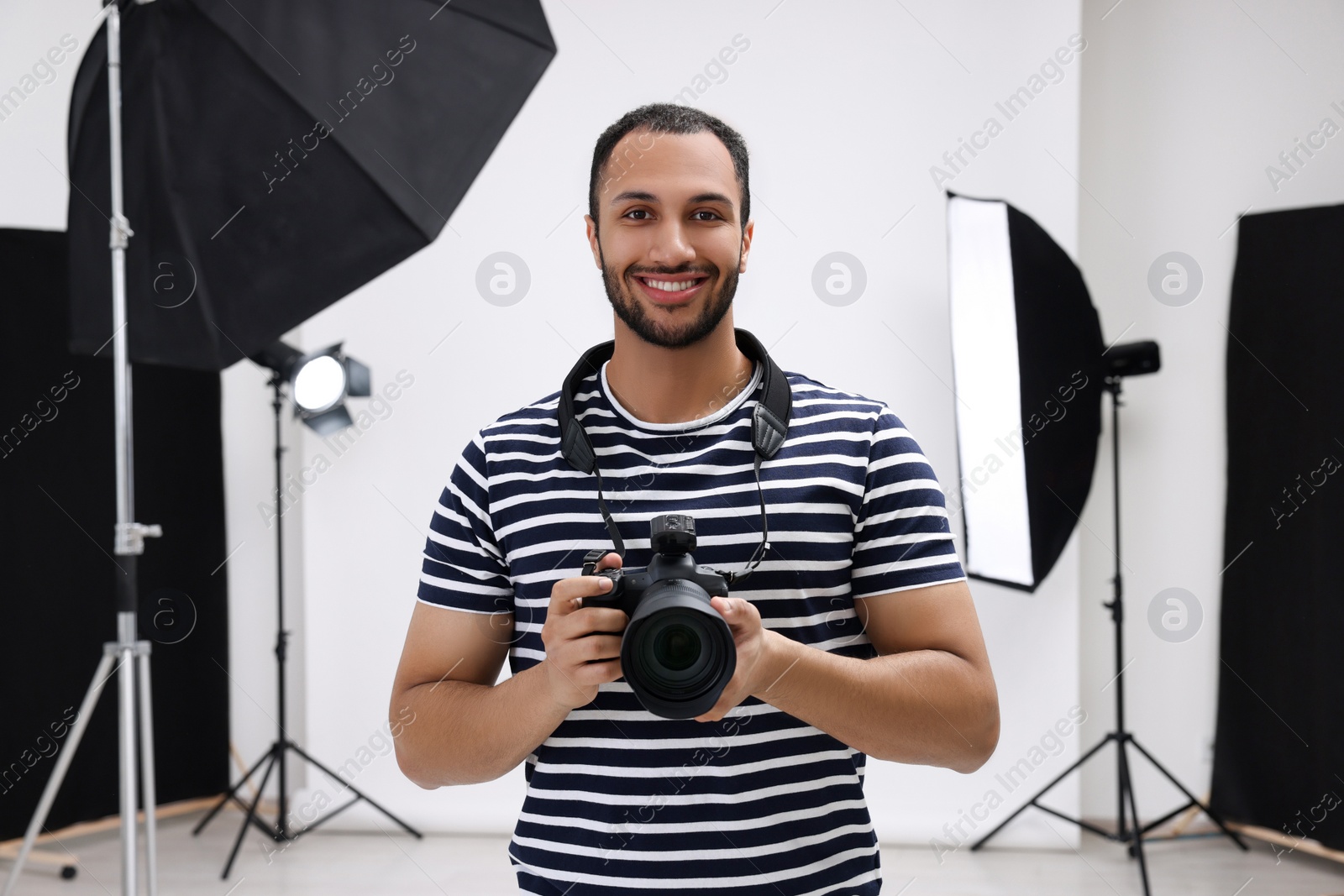 Photo of Young professional photographer with camera in modern photo studio, space for text