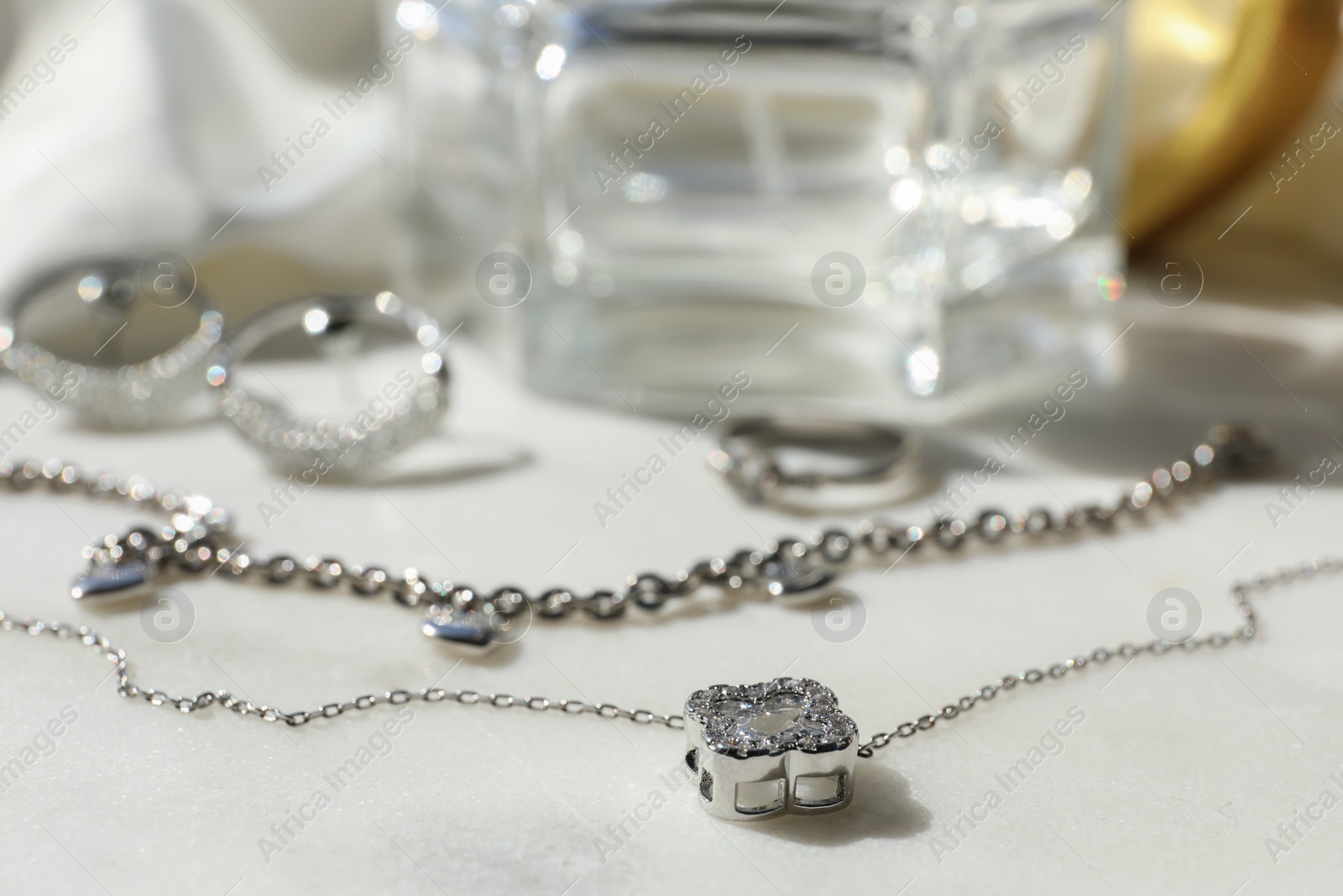 Photo of Different metal chains with pendants on white table, closeup. Luxury jewelry