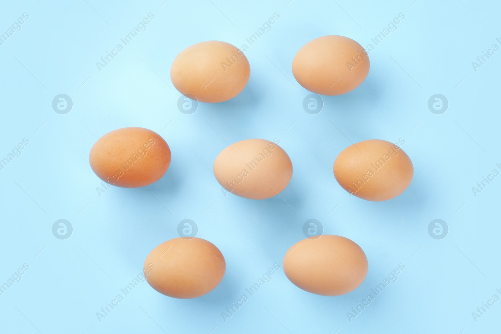 Photo of Raw chicken eggs on light blue background, flat lay