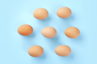 Photo of Raw chicken eggs on light blue background, flat lay