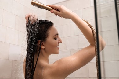 Young woman washing hair while taking shower at home