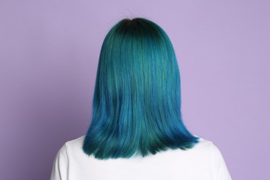 Woman with bright dyed hair on lilac background, back view