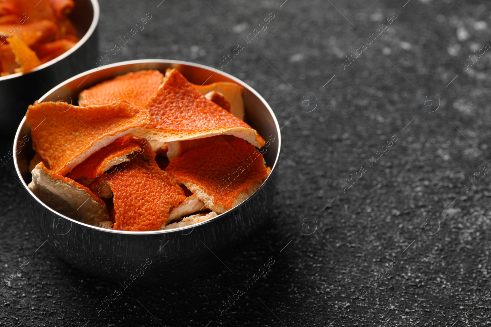 Photo of Bowls with dry orange peels on gray textured table, closeup. Space for text