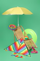 Photo of Deck chair, kite and beach accessories on green background