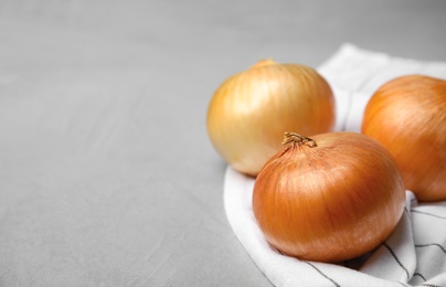 Photo of Fabric with ripe onions on grey table, space for text