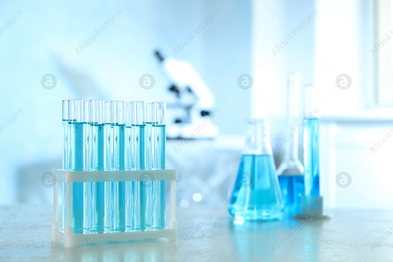 Photo of Test tubes with light blue liquid on table in laboratory. Space for text